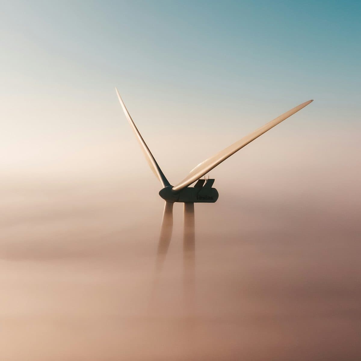 Wind turbine rising out of fog at dawn